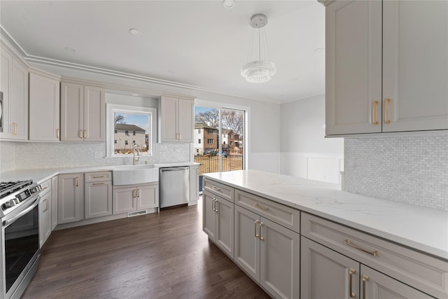 kitchen featuring pendant lighting, sink, gray cabinets, light stone countertops, and appliances with stainless steel finishes