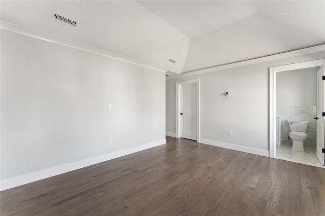 unfurnished room featuring tile walls, ornamental molding, dark wood-type flooring, and vaulted ceiling