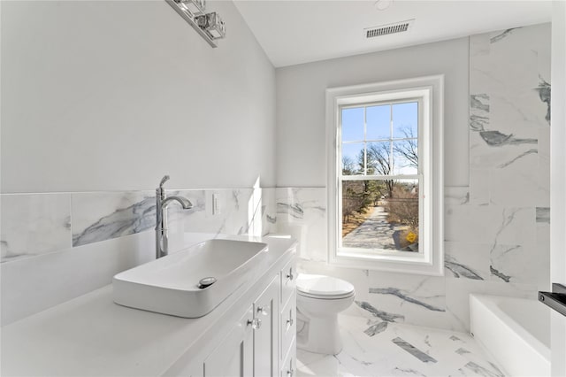 bathroom featuring vanity, toilet, tile walls, and a washtub