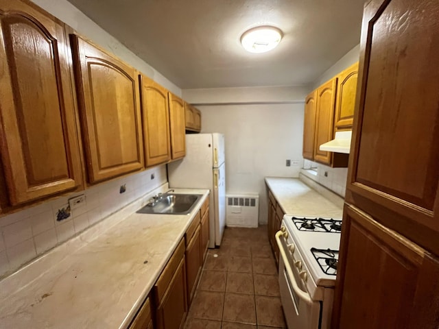 kitchen with decorative backsplash, white gas range oven, dark tile patterned flooring, and sink