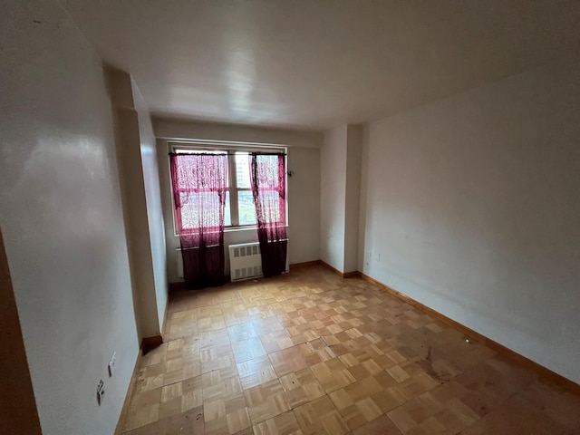 empty room with radiator heating unit and light parquet flooring