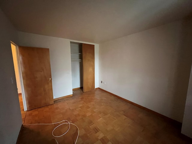 unfurnished bedroom featuring parquet floors and a closet