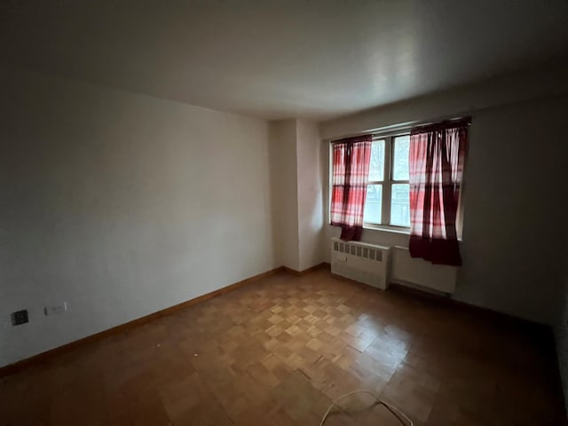 spare room featuring radiator and parquet flooring