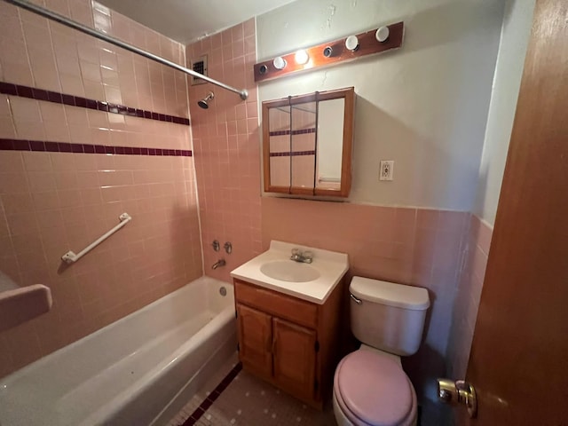 full bathroom featuring vanity, tiled shower / bath combo, tile walls, tile patterned flooring, and toilet