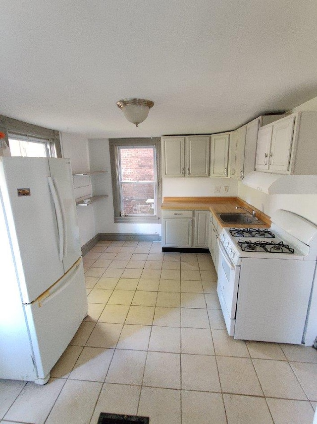 kitchen featuring sink, white cabinets, white appliances, and light tile patterned floors