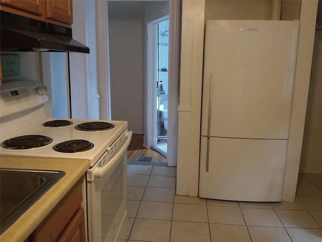 kitchen featuring light tile patterned flooring and white appliances