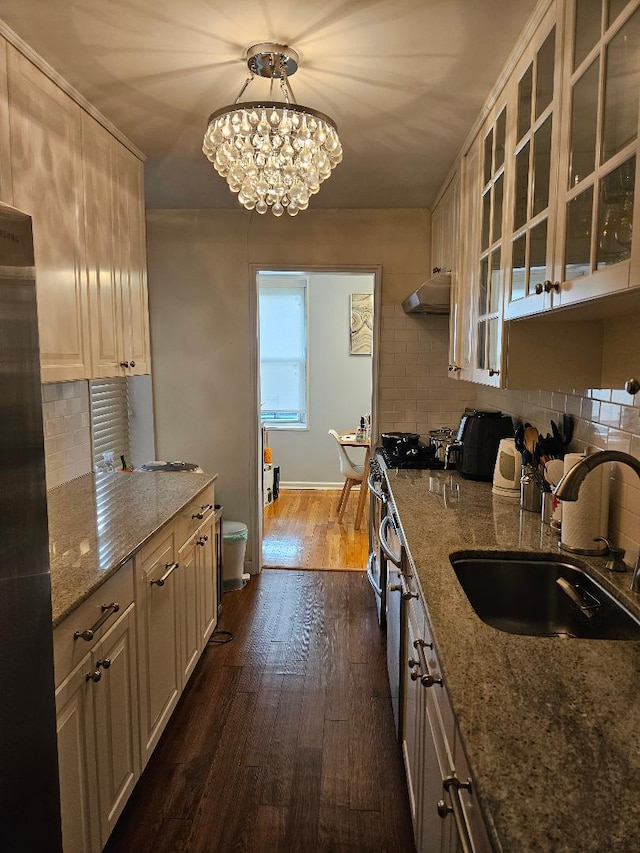 kitchen with sink, light stone counters, dark hardwood / wood-style floors, a chandelier, and decorative light fixtures