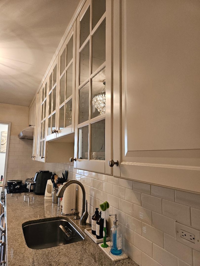 kitchen featuring stone counters, sink, decorative backsplash, white cabinets, and range