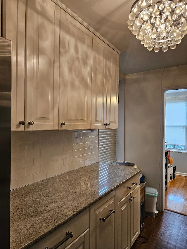 kitchen with decorative backsplash, light stone counters, and dark wood-type flooring