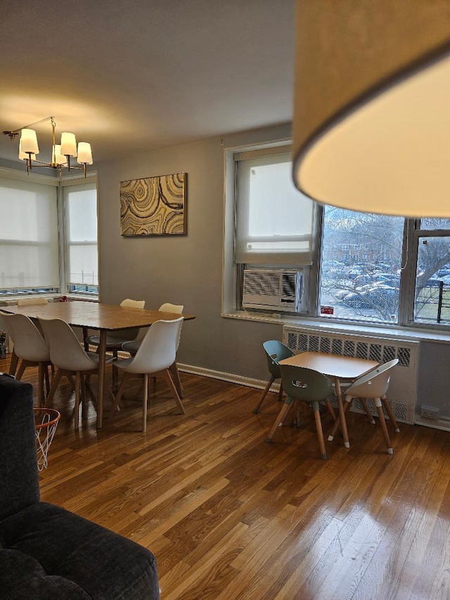 dining room featuring radiator heating unit, cooling unit, an inviting chandelier, and hardwood / wood-style flooring