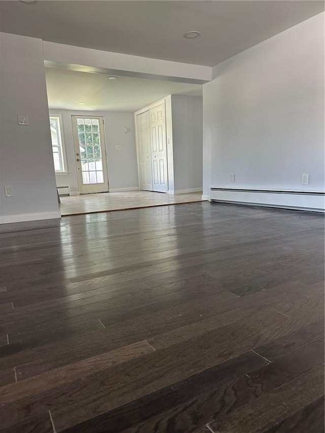 spare room featuring dark wood-type flooring and a baseboard radiator