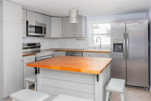 kitchen featuring stainless steel appliances, sink, backsplash, and butcher block countertops