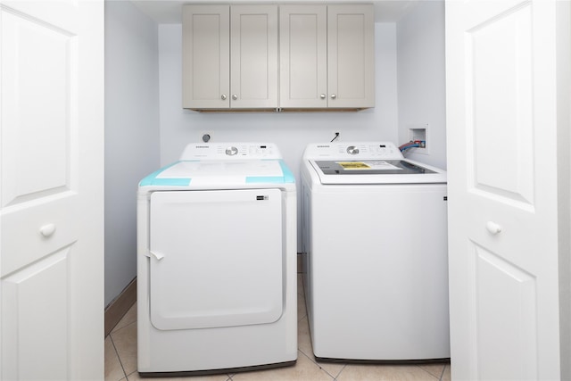 laundry room with light tile patterned floors, cabinets, and washing machine and clothes dryer