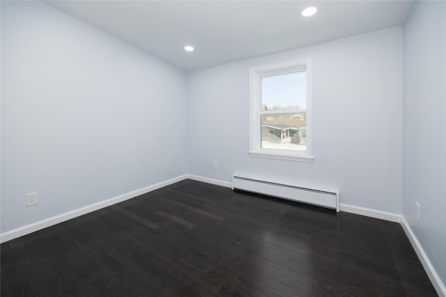 spare room with a baseboard heating unit and dark hardwood / wood-style floors