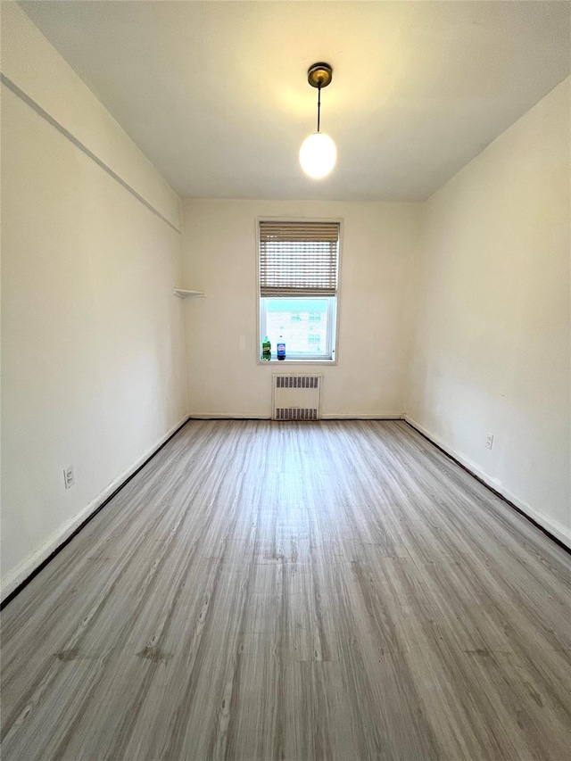 spare room featuring radiator and light hardwood / wood-style flooring