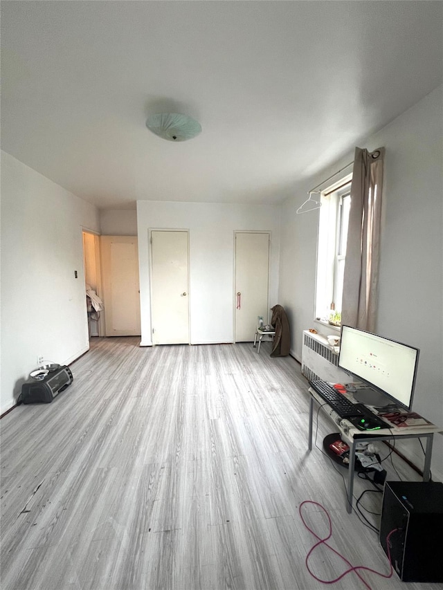 unfurnished living room featuring radiator and light hardwood / wood-style flooring