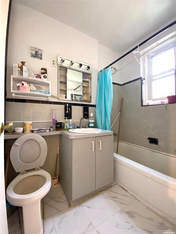 full bathroom featuring vanity, backsplash, toilet, and shower / bathtub combination with curtain