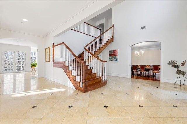 interior space featuring tile patterned flooring, ornamental molding, french doors, and a chandelier