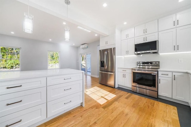 kitchen featuring decorative light fixtures, light wood-type flooring, stainless steel appliances, and white cabinetry