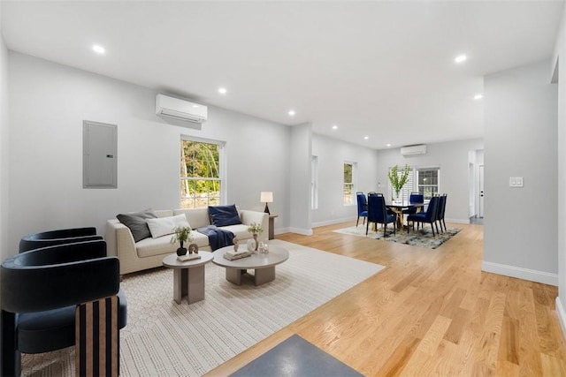 living room with light hardwood / wood-style floors, electric panel, and a wall mounted AC