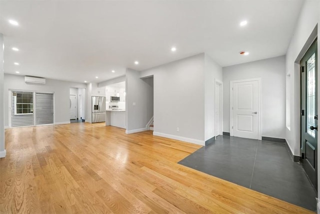 unfurnished living room with light hardwood / wood-style floors and a wall mounted air conditioner