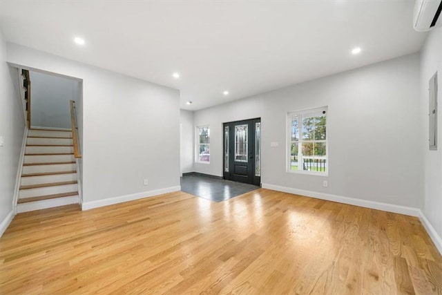 foyer featuring light wood-type flooring and a wall mounted AC