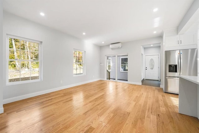 unfurnished living room featuring an AC wall unit and light hardwood / wood-style floors