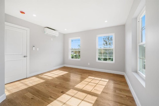 unfurnished room with an AC wall unit and light wood-type flooring