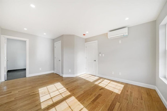 empty room with an AC wall unit and light hardwood / wood-style floors