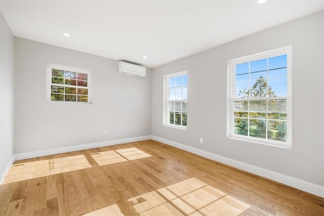 unfurnished room featuring light hardwood / wood-style flooring and a wall mounted air conditioner