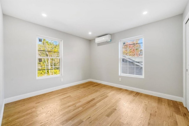 unfurnished room featuring a wall unit AC and light hardwood / wood-style floors