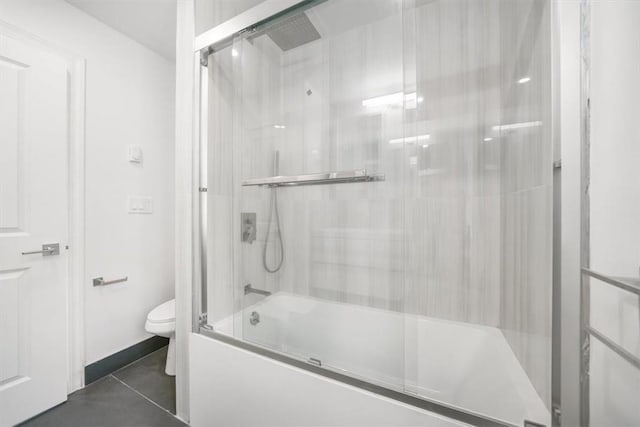 bathroom with combined bath / shower with glass door, tile patterned flooring, and toilet