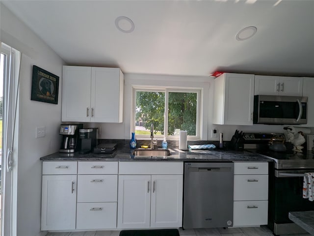 kitchen with dark stone countertops, white cabinetry, sink, and appliances with stainless steel finishes