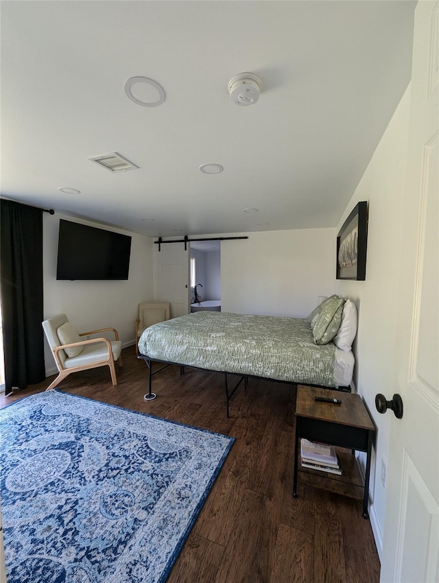 bedroom with hardwood / wood-style flooring and a barn door