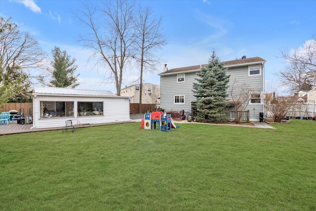 rear view of property featuring a lawn and a wooden deck