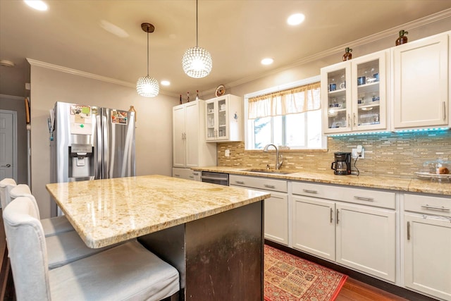 kitchen featuring white cabinetry, sink, light stone countertops, hanging light fixtures, and a kitchen bar