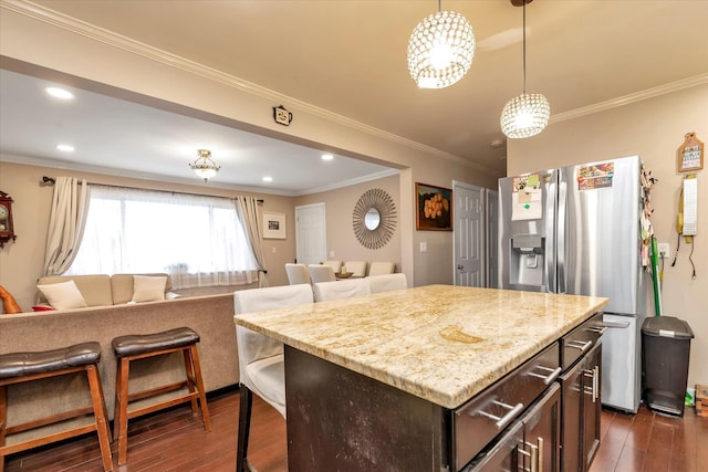 kitchen with dark wood-type flooring, stainless steel fridge with ice dispenser, ornamental molding, a kitchen island, and dark brown cabinetry