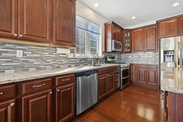 kitchen with light stone counters, sink, decorative backsplash, and stainless steel appliances