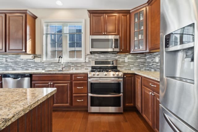 kitchen with light stone countertops, appliances with stainless steel finishes, sink, and decorative backsplash