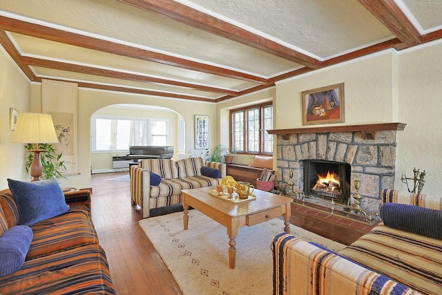 living room with hardwood / wood-style floors, a fireplace, ornamental molding, and beamed ceiling