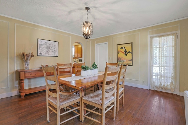 dining area with ornamental molding, a notable chandelier, and dark hardwood / wood-style flooring