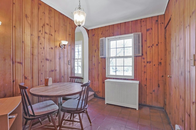 dining area featuring crown molding, radiator heating unit, and wooden walls