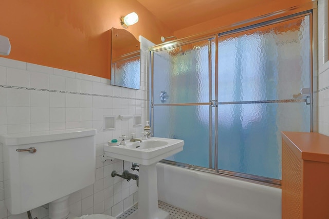 bathroom with toilet, shower / bath combination with glass door, and tile walls