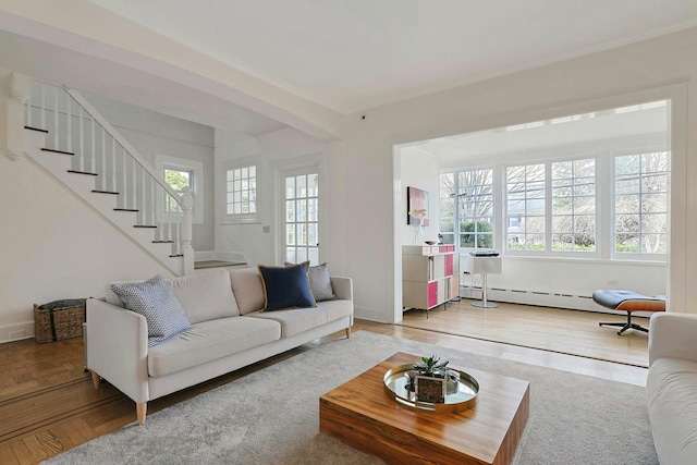 living room featuring stairway, baseboard heating, baseboards, and wood finished floors