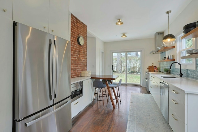 kitchen with dark wood-type flooring, decorative backsplash, appliances with stainless steel finishes, plenty of natural light, and a sink