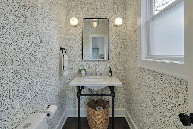 bathroom featuring wallpapered walls, toilet, and a sink