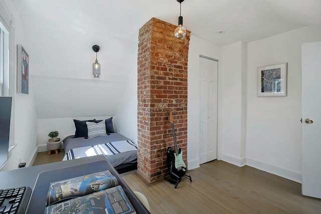 bedroom featuring lofted ceiling, wood finished floors, baseboards, and a closet