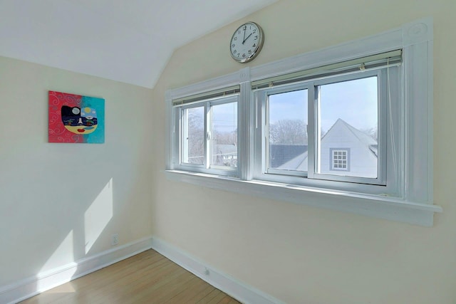 unfurnished room with vaulted ceiling, light wood-style floors, and baseboards