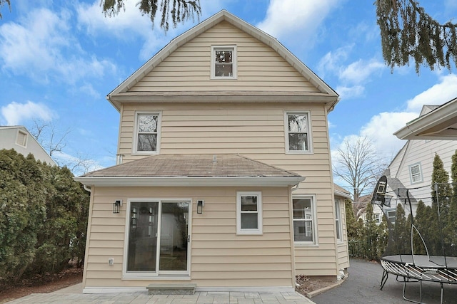 rear view of property featuring a patio and roof with shingles