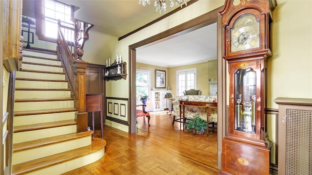 stairs featuring crown molding and parquet floors